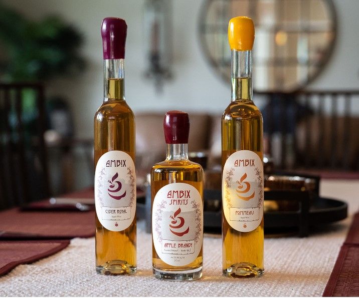 Three bottles of apple-based alcoholic beverages from Ambix Spirits on a table.