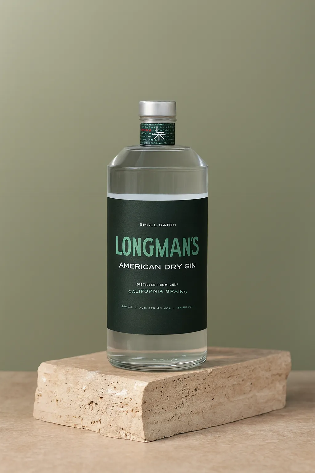 A bottle of Longman's American Dry Gin presented artfully on a stone block against a green background.