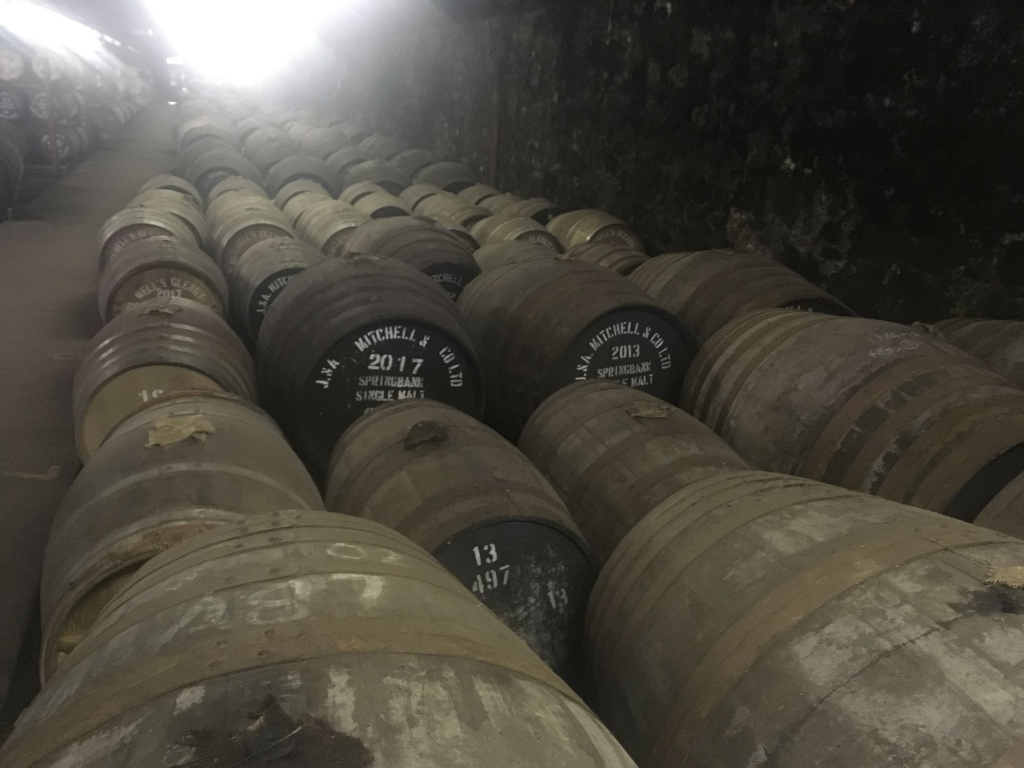 A dim warehouse full of aging oak whiskey barrels.
