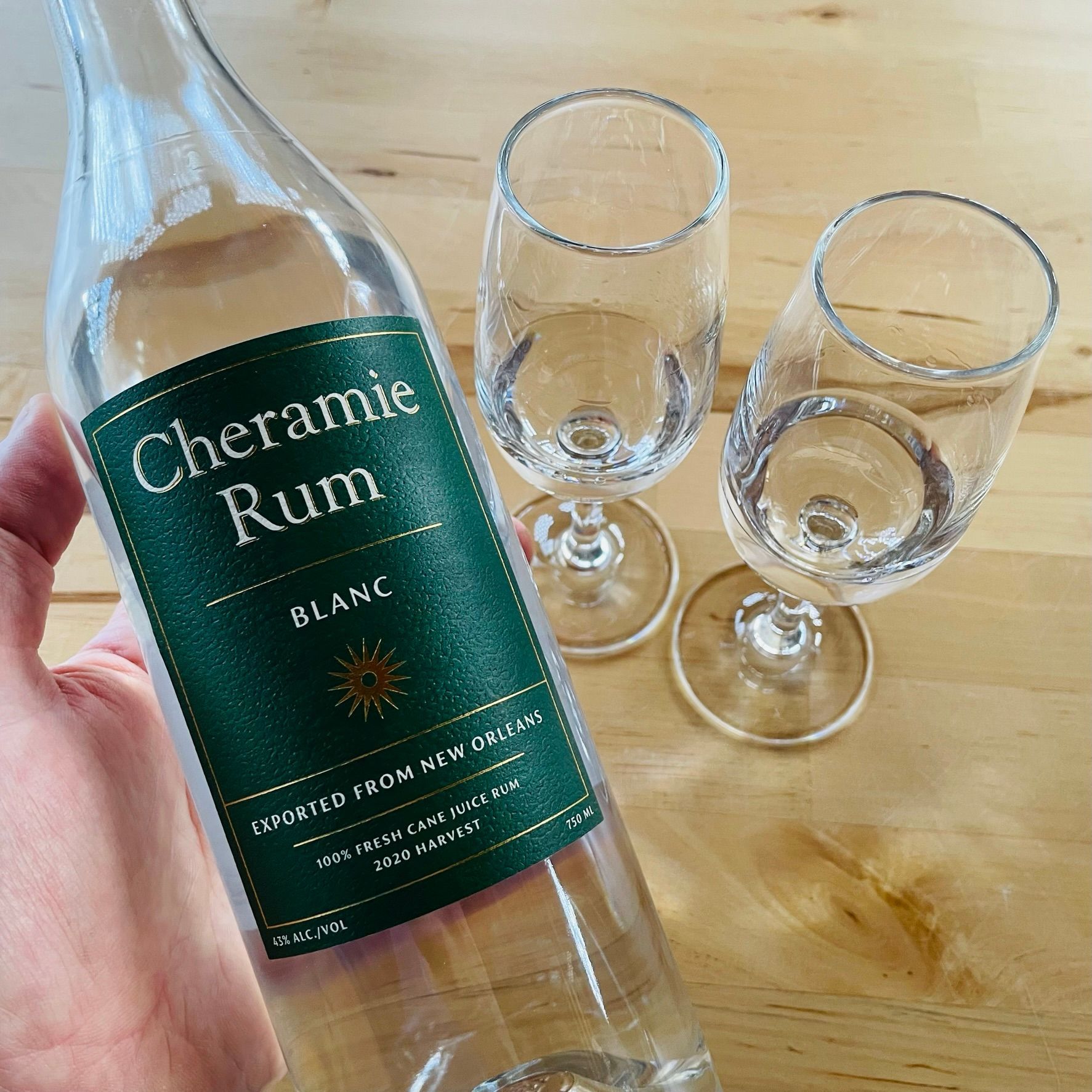 A bottle of Cheramie Rum Blanc with two tasting glasses.