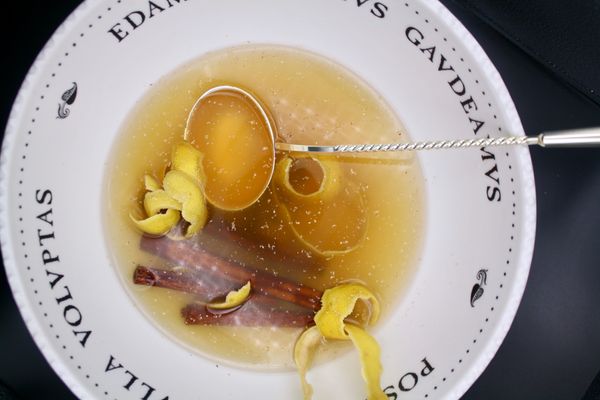 A punch bowl seen from top down, filled with punch, lemon peels, cinnamon sticks, and topped with nutmeg.