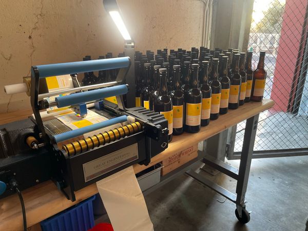 A worktable with automatic bottling machine and bottles of whiskey.
